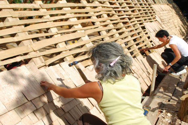 Two volunteers laying hand made shingles