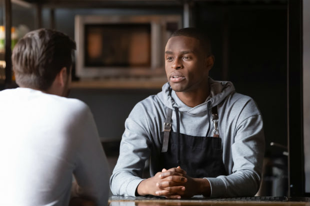 Photo of 2 men chatting at a table 